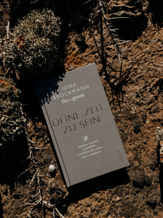 Nina Brockmann hat ein Buch geschrieben. Der Titel ist: »deine Zeit zu sein«. Es liegt auf der braunen Erde – daneben ein Schneckenhaus